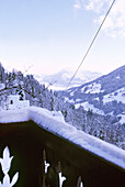 Blick vom Balkon eines schweizer Chalets auf schneebedeckte Berge