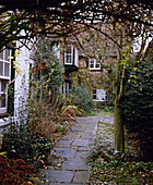 Exterior of detached whitewashed cottage and garden