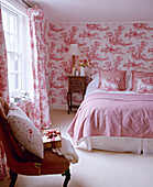 Double bed in pink bedroom with Toile de Jouy wallpaper and coordinating curtains