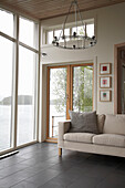 Contemporary chandelier above sofa in bay window overlooking lake