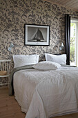 Wooden chair next to double bed in bedroom with pattern wallpaper