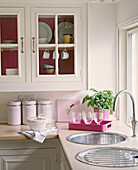 A detail of a modern country kitchen decorated in neutral colours sink tap glass fronted cabinet pudding in dish glasses