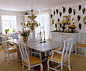 Wooden table and white wood Gustavian chairs in country style dining room