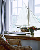 Wicker chair in front of window sill with model boat
