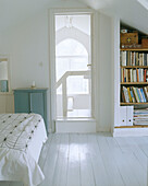 Bedroom with a white painted floor and a inbuilt bookshelf behind the door