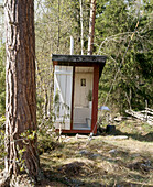 Rustic outhouse toilet surrounded by woods
