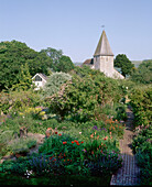A view of a country garden stone church tower flower borders shrubs trees
