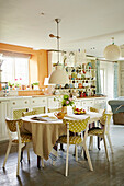 Upholstered chairs at kitchen table in Cotswold home of textile designer, UK