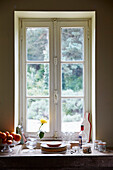 Plates and oranges with single stem rose in window Lot et Garonne, France