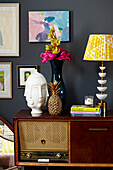 Books and ornaments with yellow lamp on vintage sideboard in Brighton home East Sussex, UK