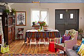 Wooden dining chairs at table with upholstered armchair in Brighton barn conversion East Sussex, UK