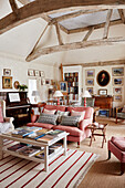 Bookcases and seating with piano in double height living room of 17th century Hampshire barn conversion England, UK