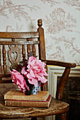 Schnittblumen und Bücher auf einem Vintage-Stuhl mit Toile de Jouy-Tapete in einem Haus in Hampshire aus dem 17. Jahrhundert