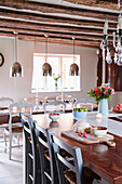 Frühstücksbar und Esstisch mit Hängeleuchten in einer unter Denkmalschutz stehenden Bauernhausküche in Kent, Großbritannien
