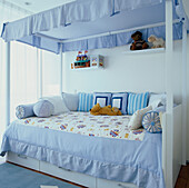 Child's four poster bed with storage draws and blue decor