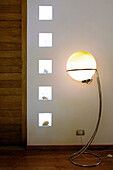 Living-room with glass bricks embedded with seashells and lit orb standard lamp