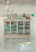 White painted kitchen dresser with pastel coloured glass tableware