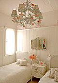 Weiß gestrichenes Kinderzimmer mit floral gemusterten Kronleuchterschirmen