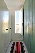 Narrow hallway with panelled walls and striped floor rug