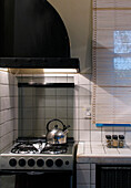 Wasserkocher auf dem Kochfeld in einer gefliesten Küche mit Abzugshaube