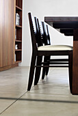 Dark wood chairs set at table on polished cement floor