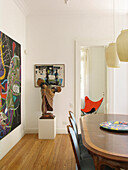 Modern art work and sculpture from Brazil in dining room with pendant lights and wooden table