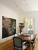 Dining room table with light blue upholstered chairs pendant lights and art work from Brazil