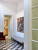 Upholstered bench seat and armchair in hallway with modern art