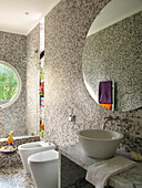 Großer Spiegel über dem Waschbecken in einem grau gefliesten Badezimmer