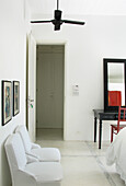 Schlafzimmer mit Betonboden, Carrara-Marmor-Bordüren und einem englischen Schreibtisch mit passendem Stuhl und Spiegel