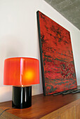 Glass lamp and shade with Oriental artwork on wooden sideboard