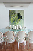 Modern art in dining room with glass topped table and French style director chairs