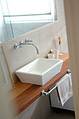 Ceramic wash basin and wall mounted mixer taps under mirror
