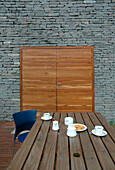 Moderner Essbereich im Außenbereich mit unbearbeiteter Steinwand und Doppeltüren aus Holz