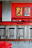 Recycled kitchen counter with Lapacho top and cast iron stools with black leather seats plastered walls painted red