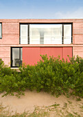 House exterior painted pink with sliding shutters and balcony