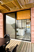 View through sliding doors to summerhouse interior with concrete floors and Japanese folding screen