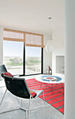 Metal framed chairs in white beach house living room with striped red rug