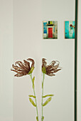 Hand crafted flower reflected in bathroom mirror with artwork