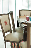 Embroidered detail on dining chair at table with notebook