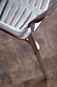 Arm and seat of polished metal chair