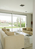 Cream sofas in living room with large glass sliding doors