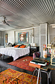 Schlafzimmer mit verzinktem Metall, chinesischen Möbeln und gewebten Teppichen