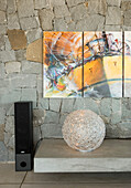 Moderne Kunst hängt an einer freiliegenden Steinwand mit Lautsprechern und Beleuchtungskörpern