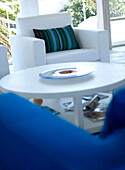 White armchair with striped green cushion and circular coffee table