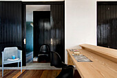 Chair at wooden desk with view through panelled black sliding doors to hallway
