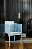 Turquoise wooden chair in black panelled room