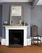 Silver framed mirror on painted original fireplace in grey bedroom with coir matting