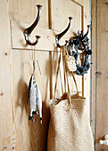 Tasche aus Naturfasern und Kranz aus Trockenblumen hängen an einer Holztür