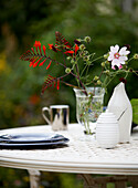 Vase of flowers and plates on garden table